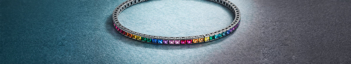 A black rhodium-plated sterling silver tennis bracelet with black nano stones and a blue stone accent on the clasp.