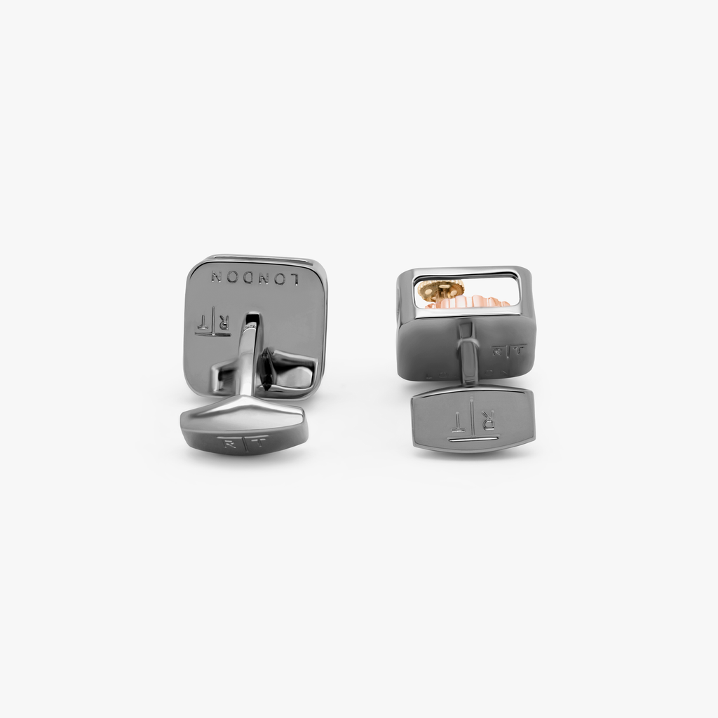 A pair of black gunmetal plated square gear cufflinks with visible mechanical gears inside the links.