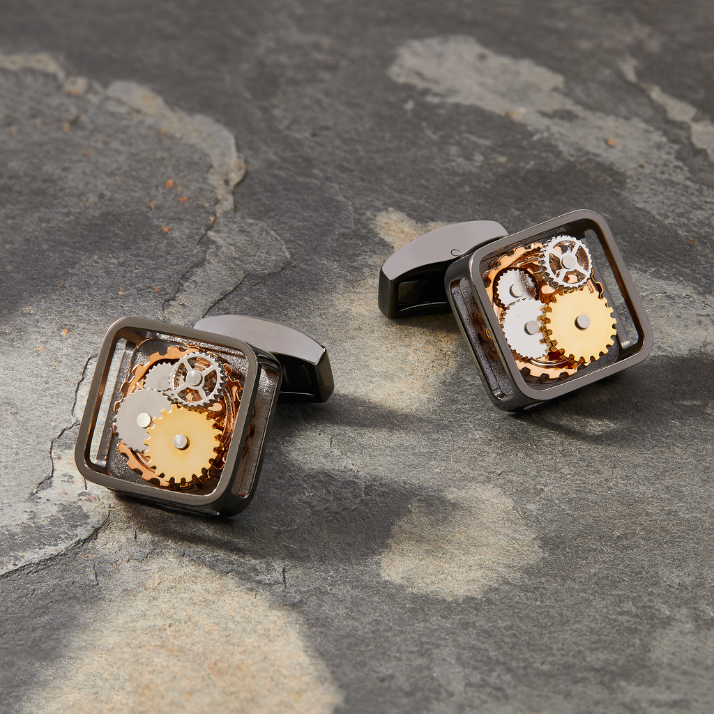 A pair of black gunmetal plated square gear cufflinks with visible mechanical gears inside the links.