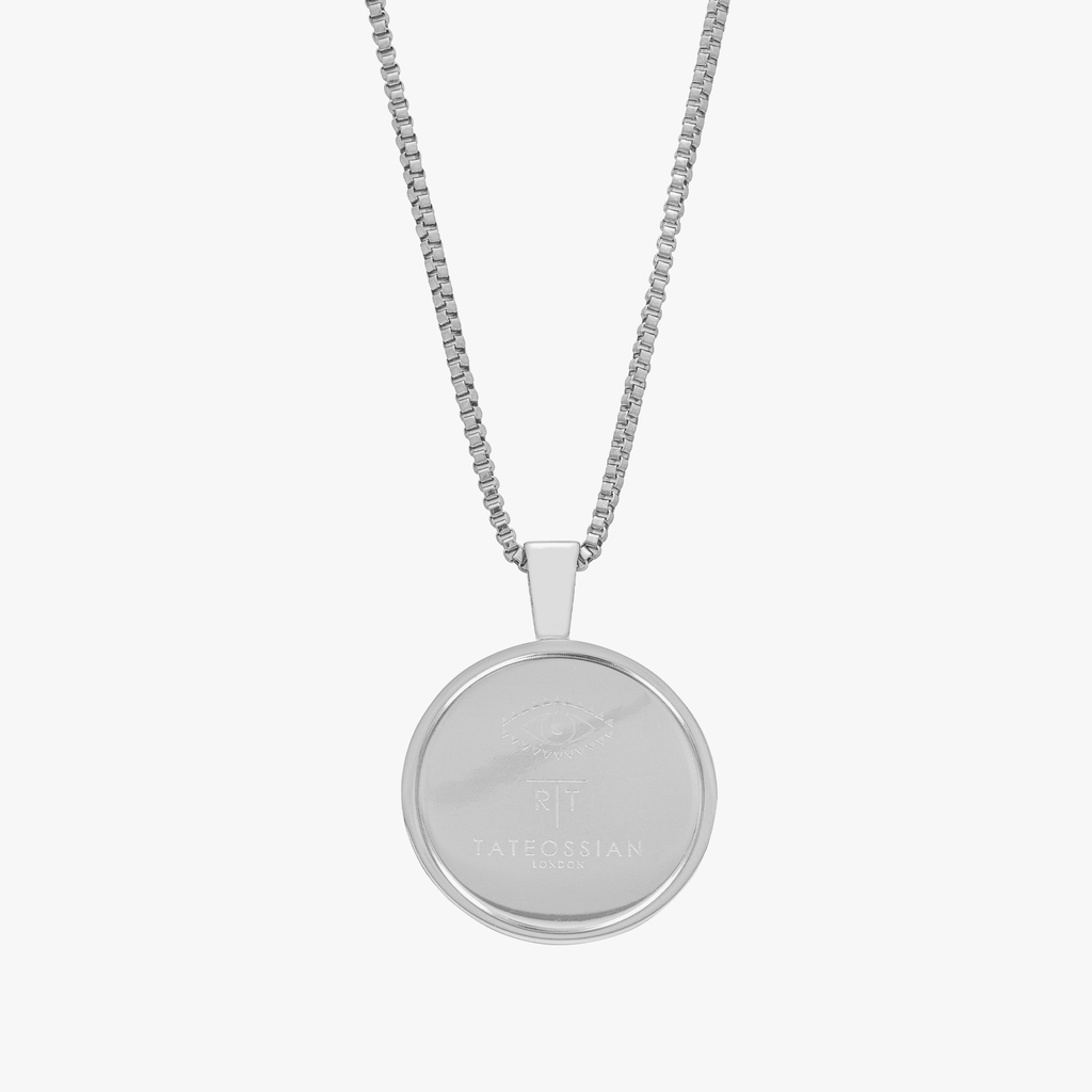 A stainless steel rotating compass amulet necklace with engraved symbols, attached to a silver chain.