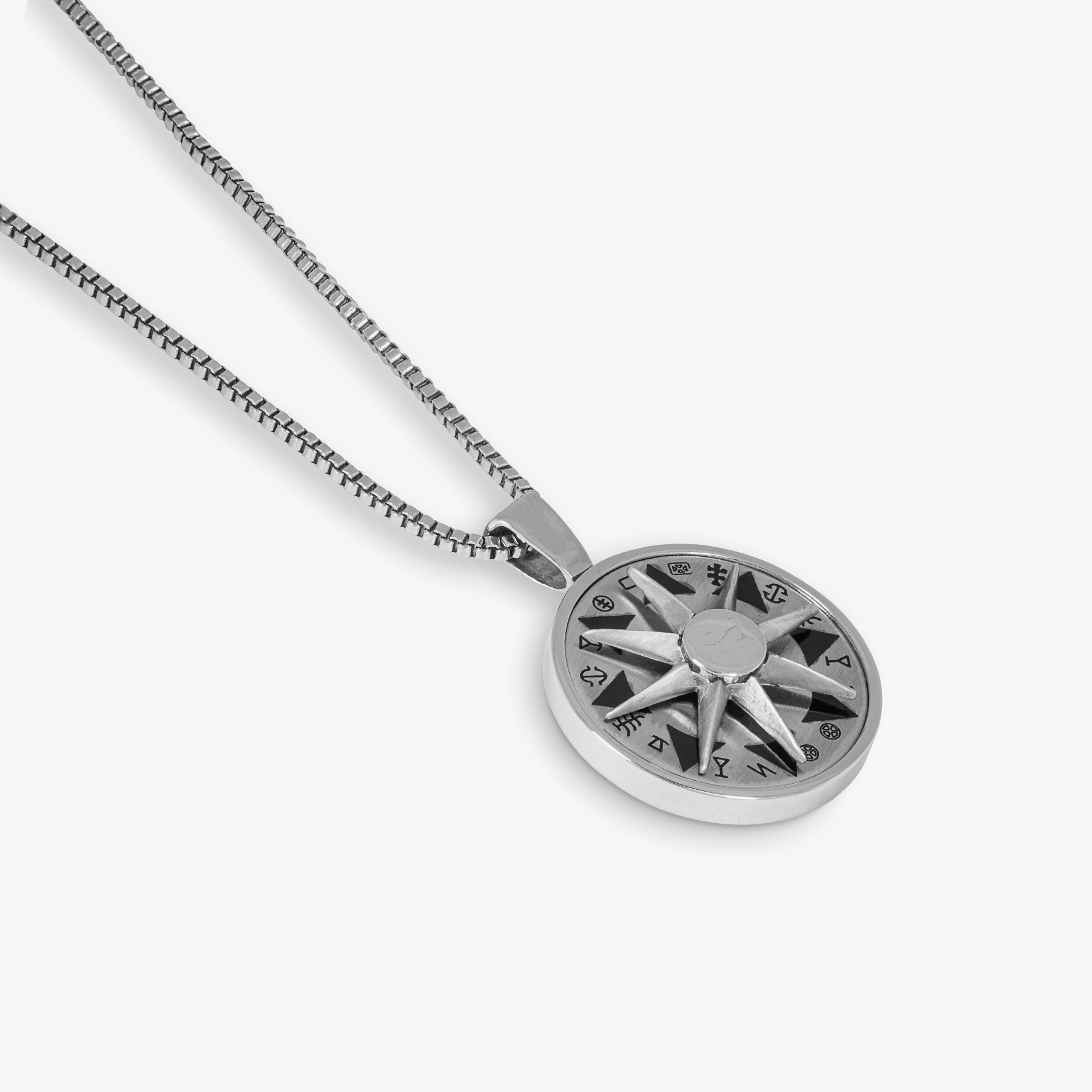 A stainless steel rotating compass amulet necklace with engraved symbols, attached to a silver chain.