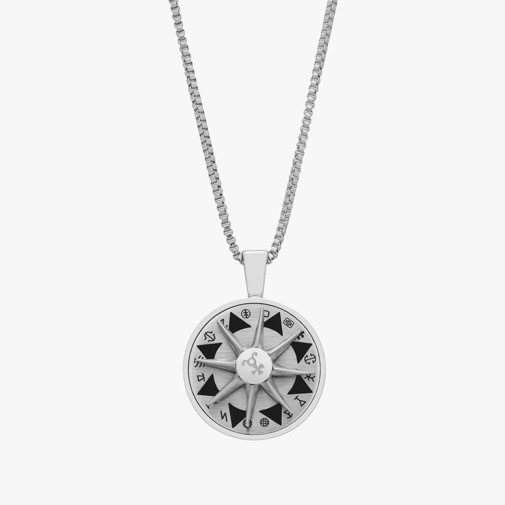 A stainless steel rotating compass amulet necklace with engraved symbols, attached to a silver chain.