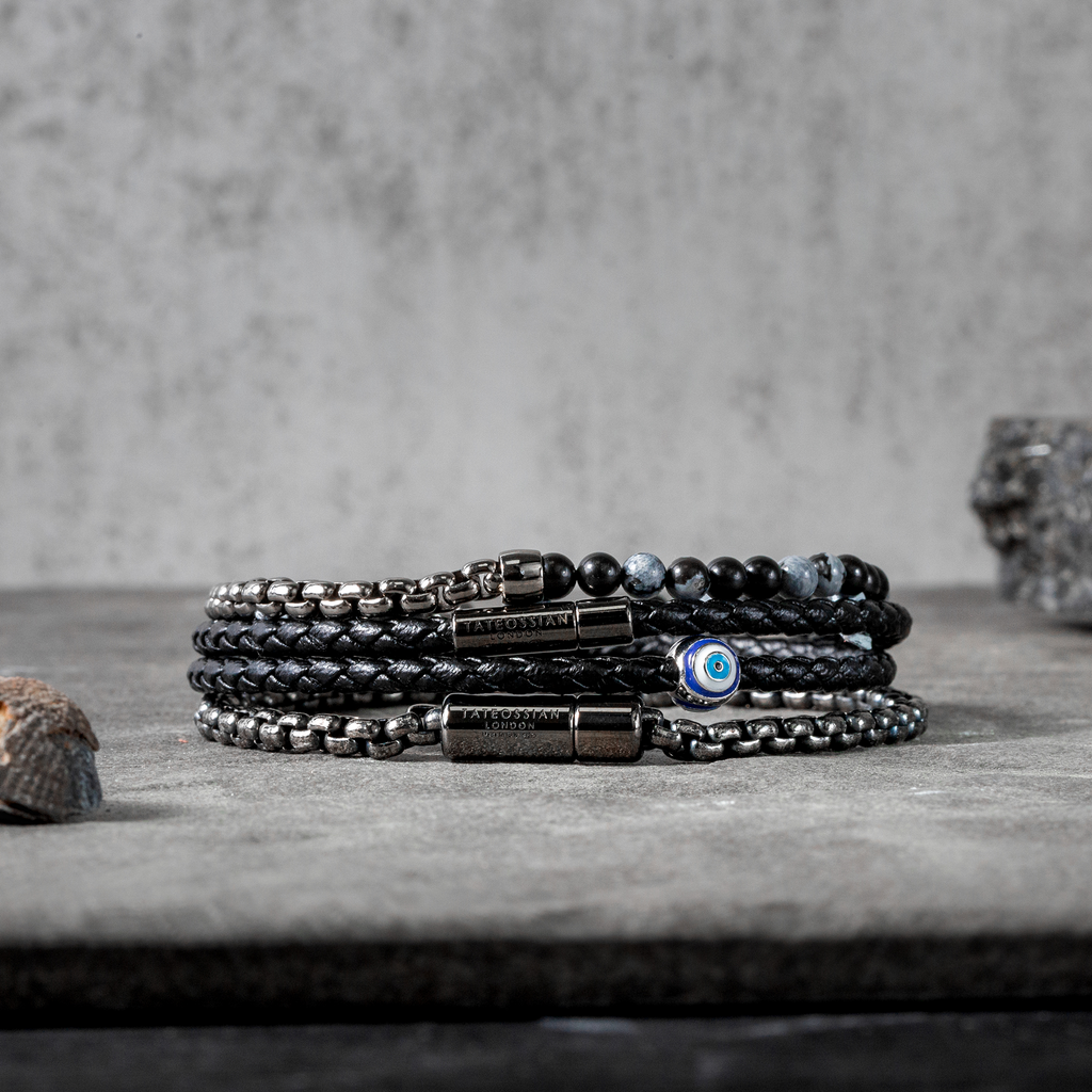 A black eco-friendly leather bracelet with a ruthenium-plated silver evil eye charm and a metal pop-clasp.
