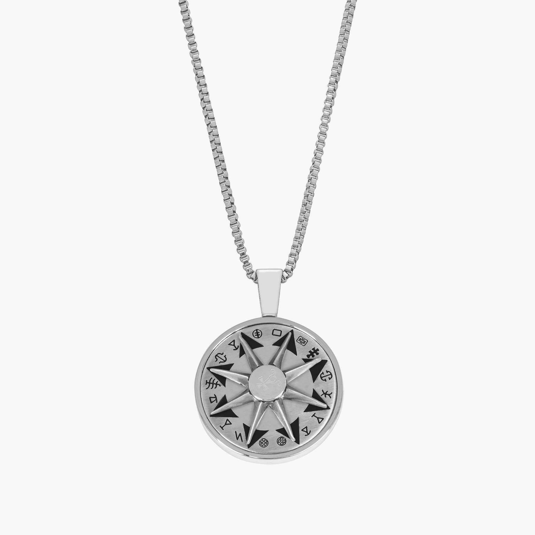 A stainless steel rotating compass amulet necklace with engraved symbols, attached to a silver chain.