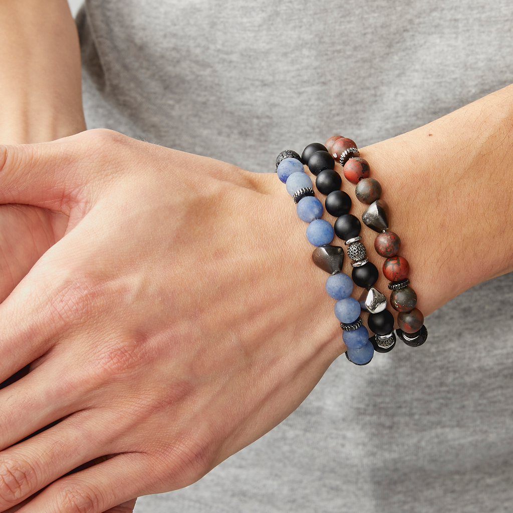 A bracelet with a mix of dark and light blue beads, some shaped like lava rocks, and black rhodium plated sterling silver detailing.