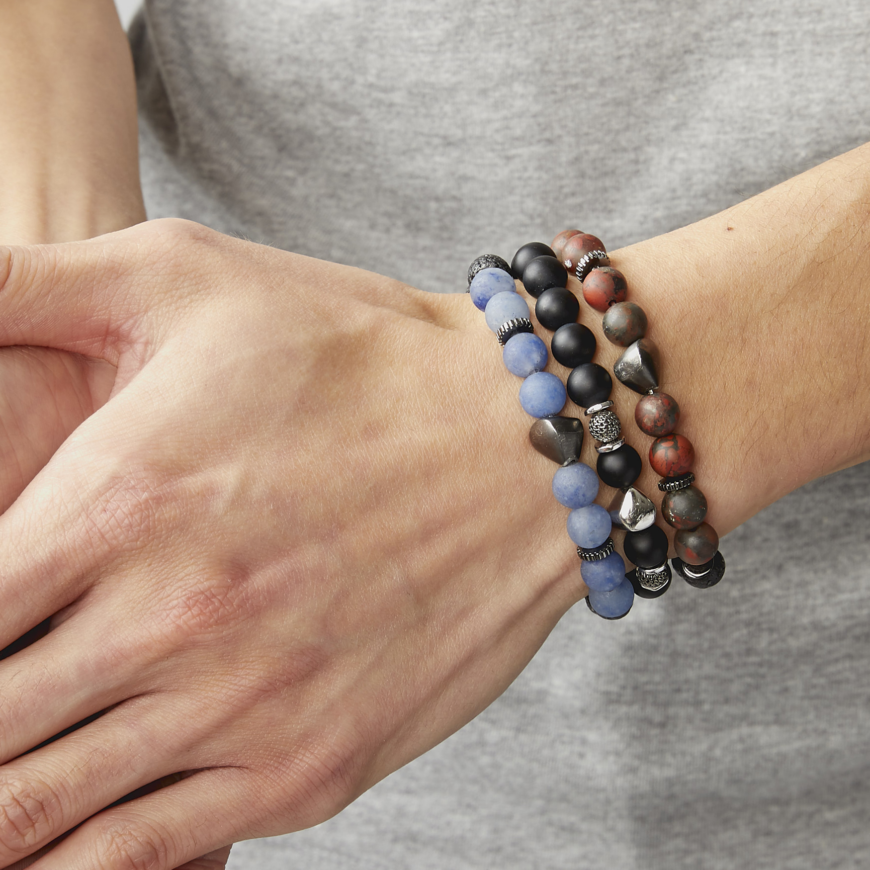 A bracelet with a mix of dark and light blue beads, some shaped like lava rocks, and black rhodium plated sterling silver detailing.