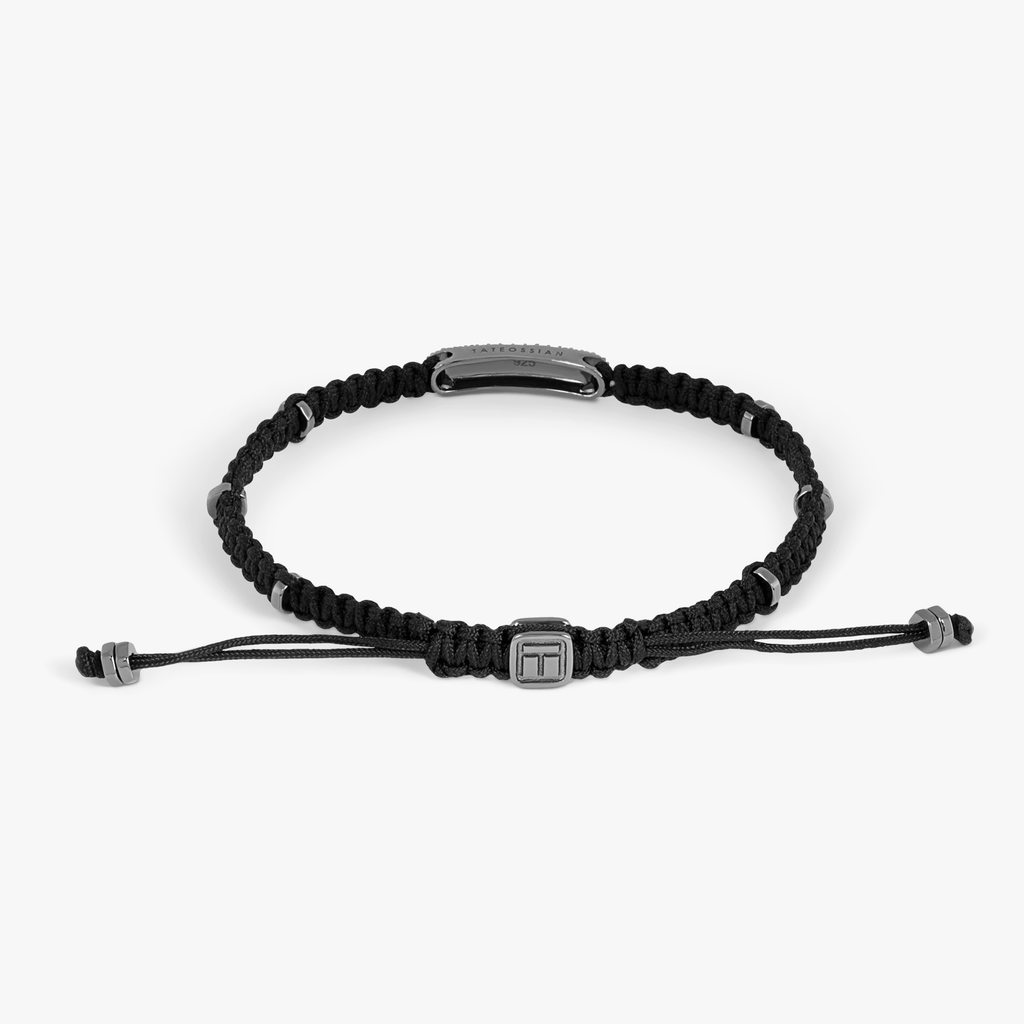 A black macrame bracelet with emerald accents and silver disc elements.
