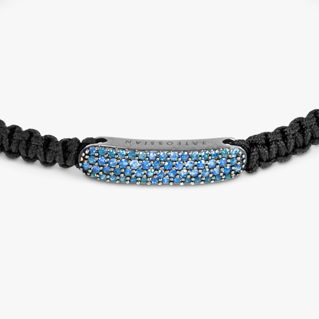 A black macrame bracelet with emerald accents and silver disc elements.