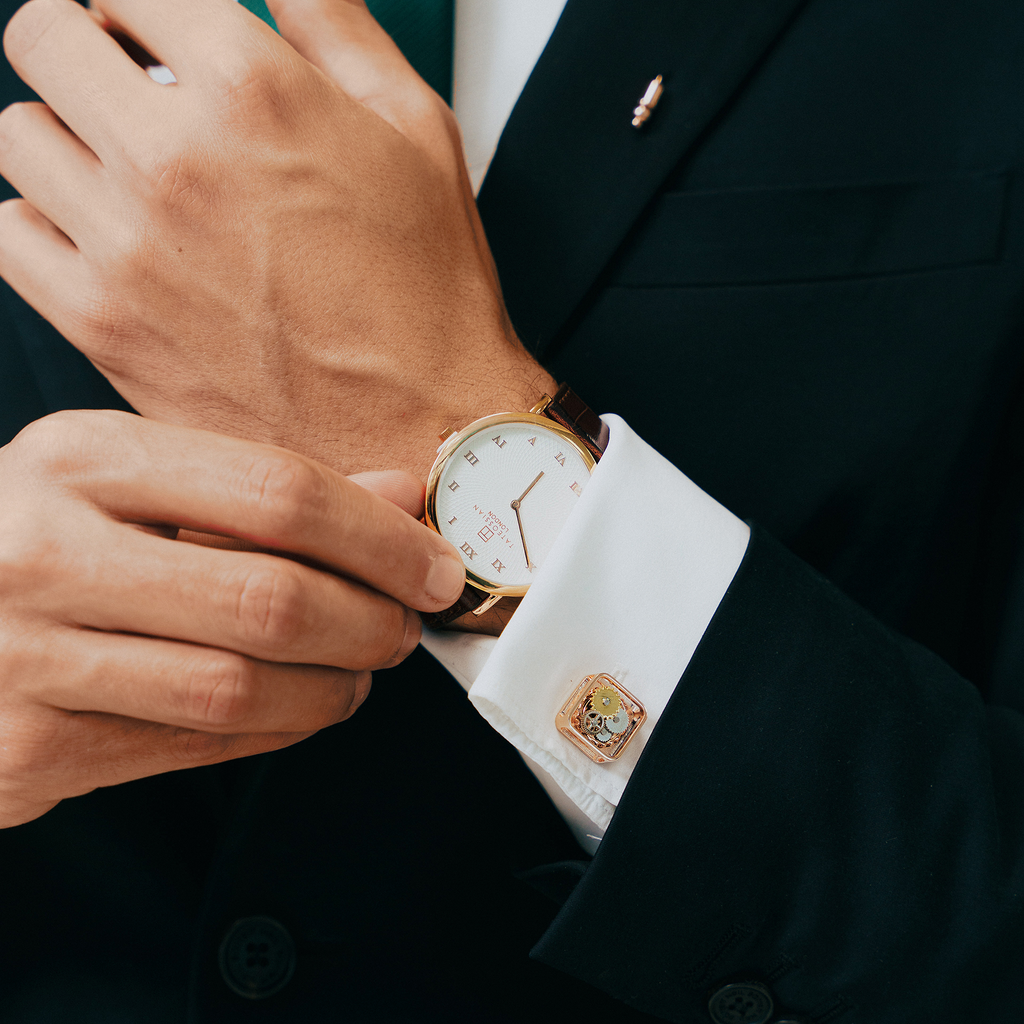 A pair of rose gold-plated square gear cufflinks with visible mechanical gears inside.