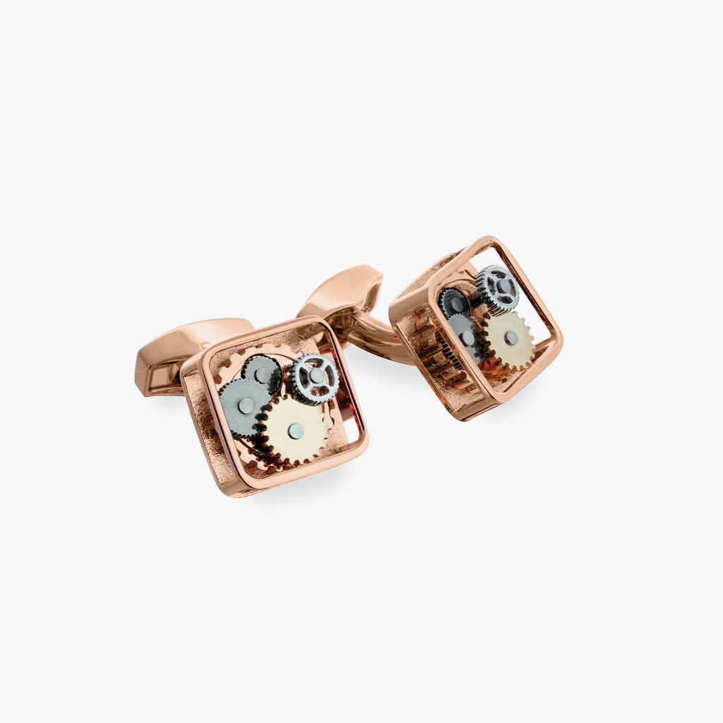 A pair of rose gold-plated square gear cufflinks with visible mechanical gears inside.