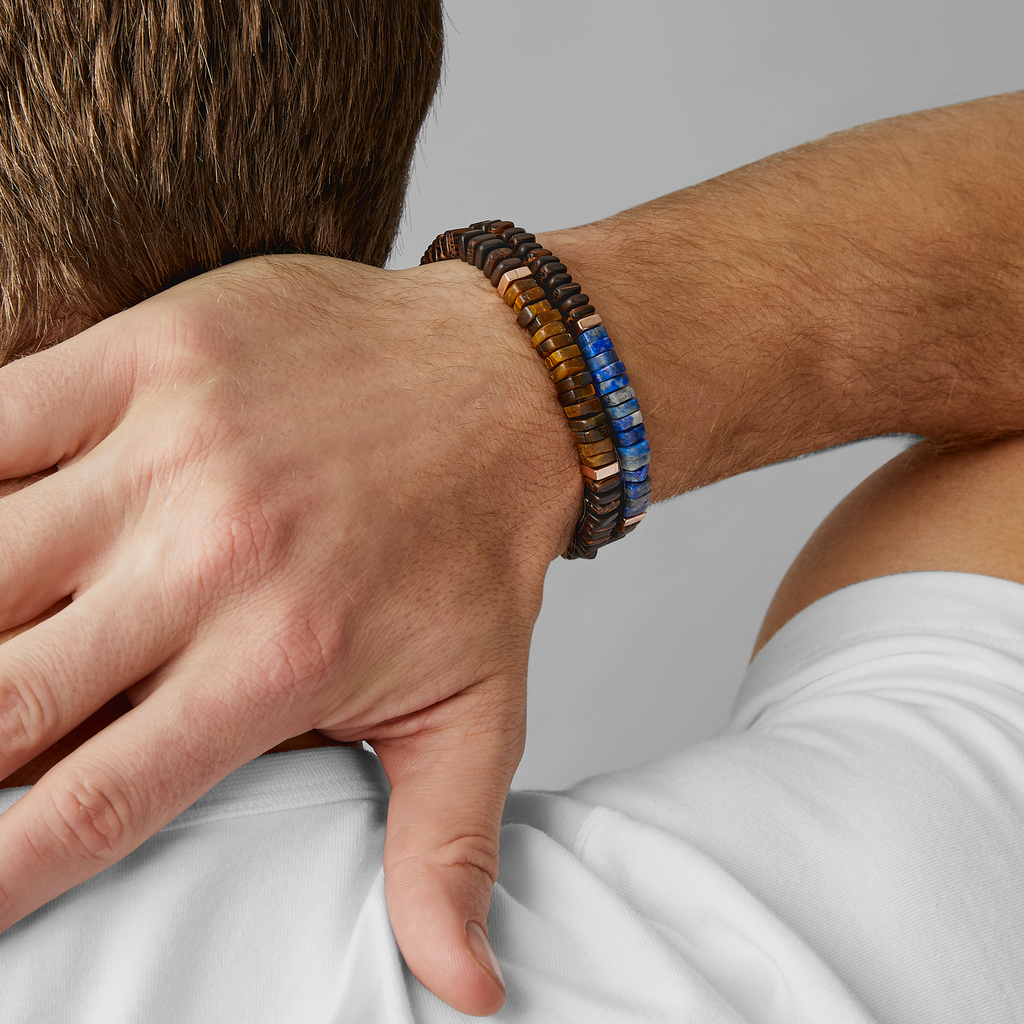 A bracelet with a combination of dark and light wood beads, accented by rose gold-colored sterling silver discs and a central lapis stone.