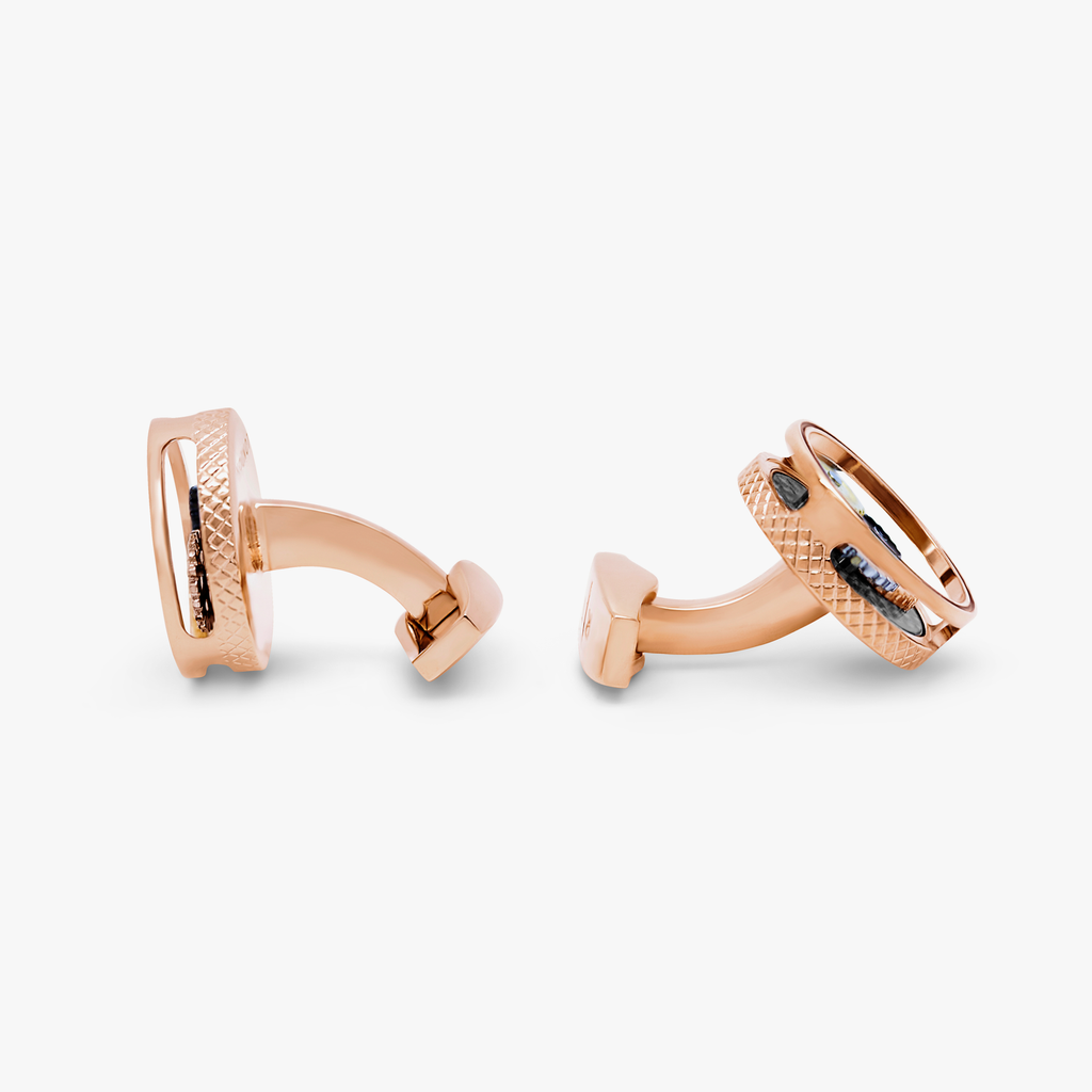 A pair of round gear cufflinks with a rose gold finish and visible mechanical gears inside.